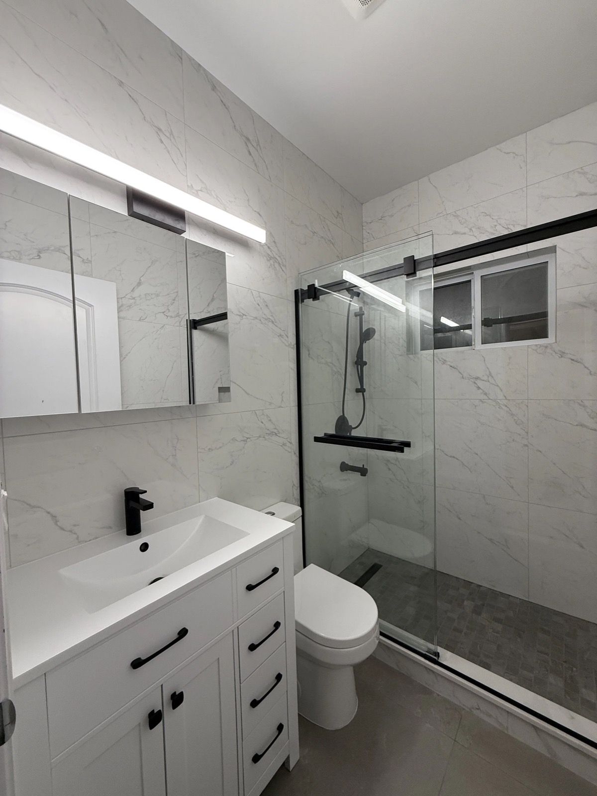 Modern bathroom renovation with glass shower, black fixtures and wooden vanity