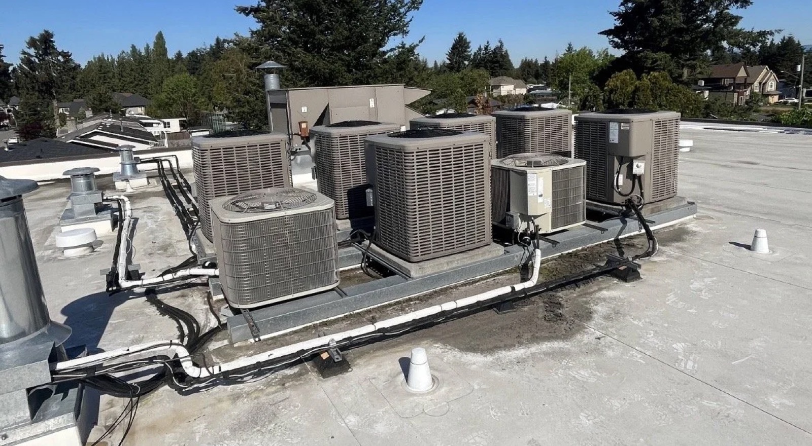 Rooftop HVAC heat pump and air conditioning units undergoing preventative maintenance for a commercial building