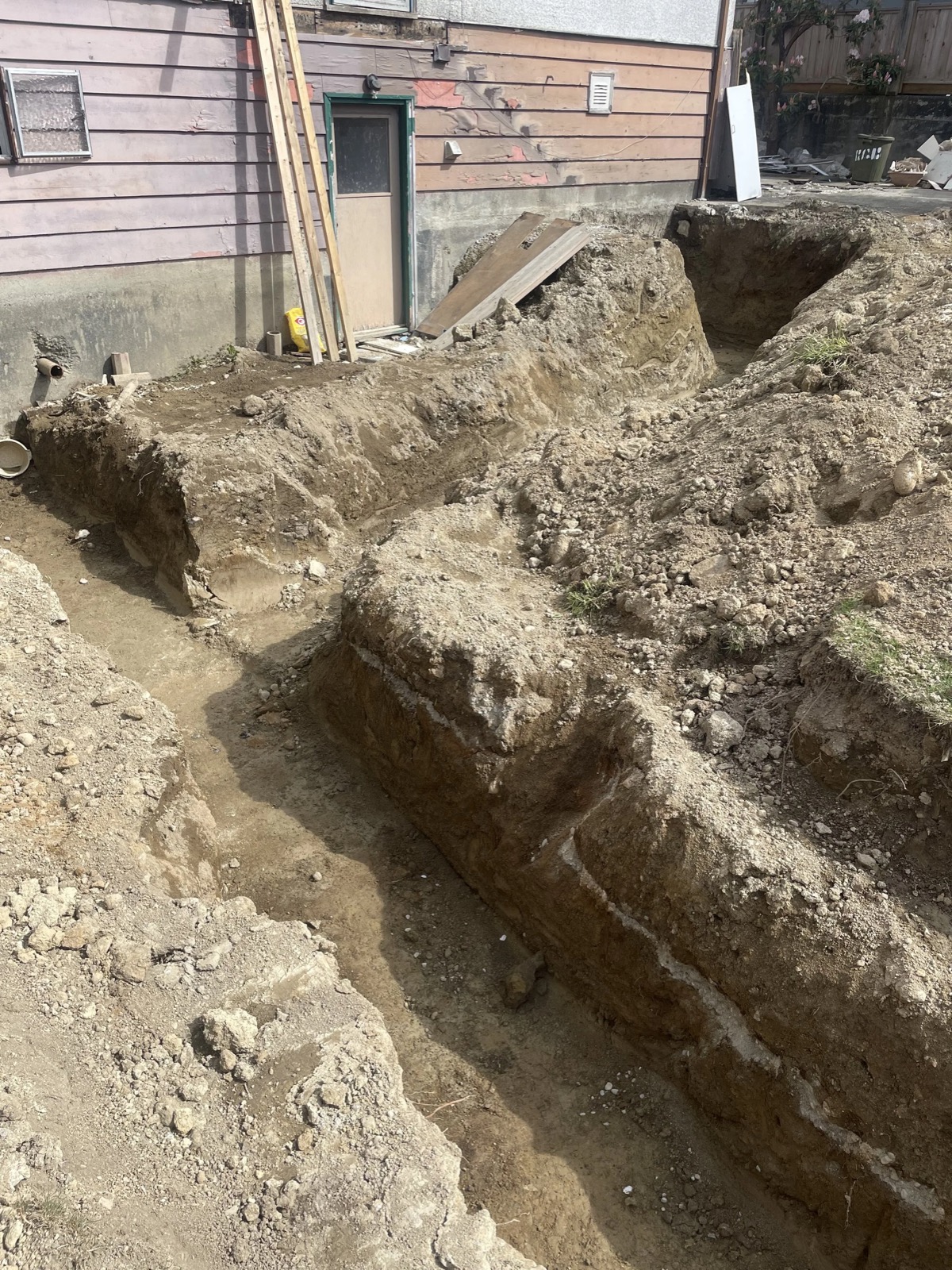Trenching for groundwork to install water and drainage lines during a full house renovation